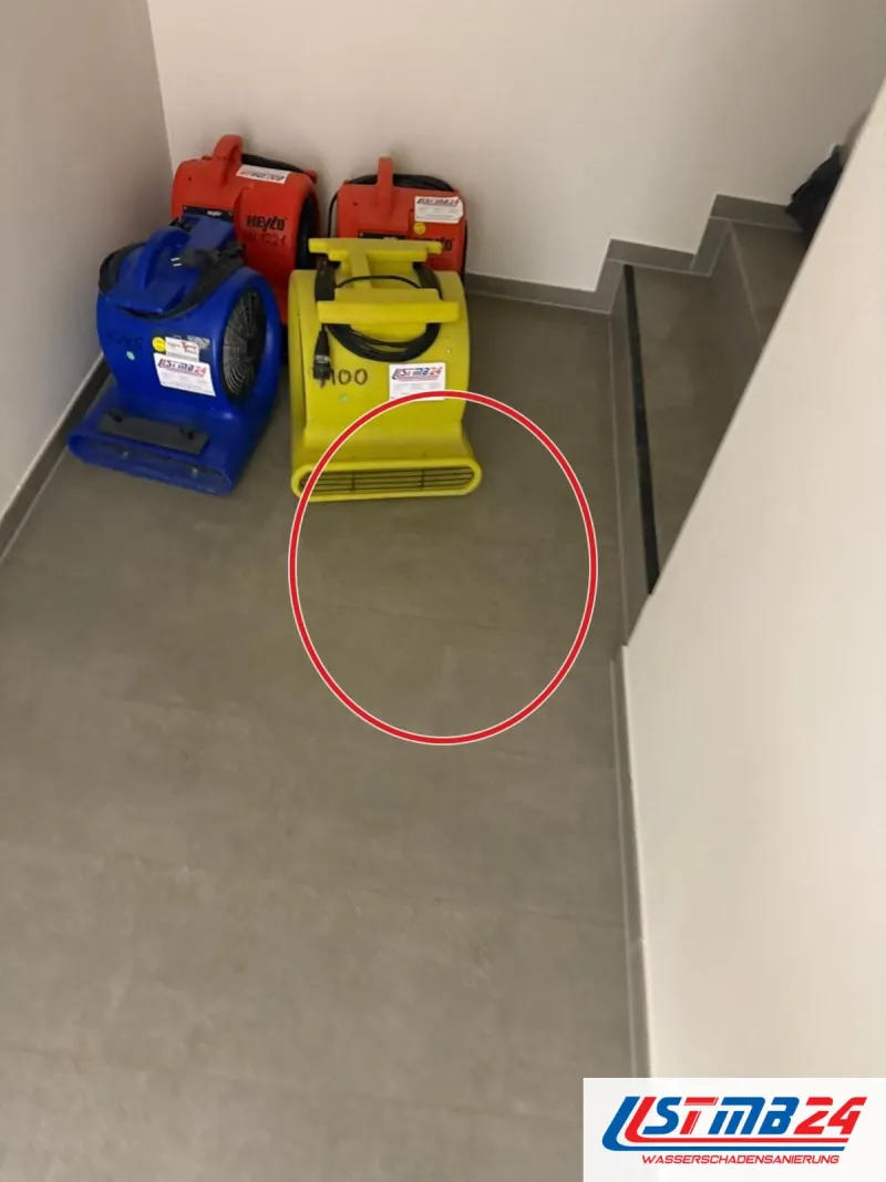 Vier Gebläse in Rot, Blau und Gelb am Fuß einer Treppe, ein roter Kreis markiert die Stelle