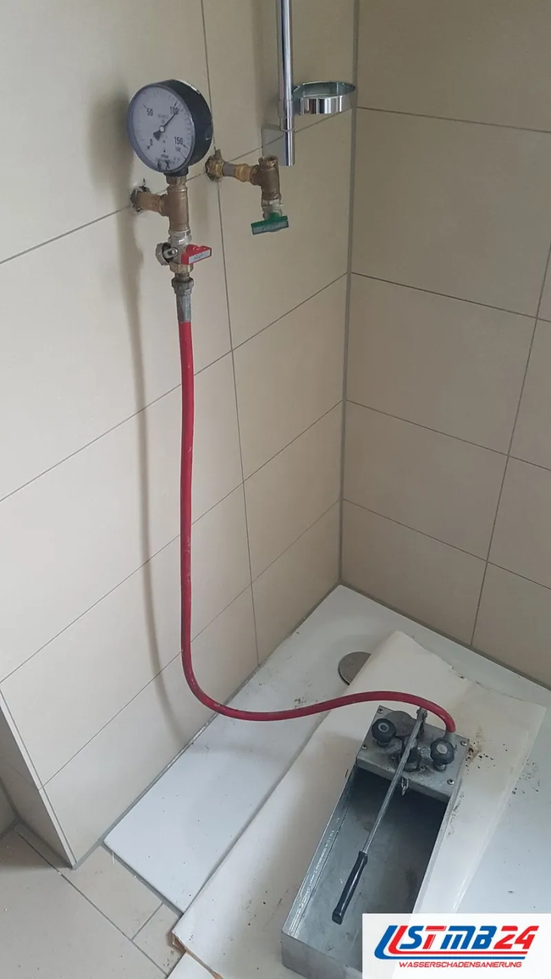 Manometer mit Kugelhähnen an den Duschanschlüssen, der rote Schlauch führt zur Prüfpumpe auf der abgedeckten Duschtasse