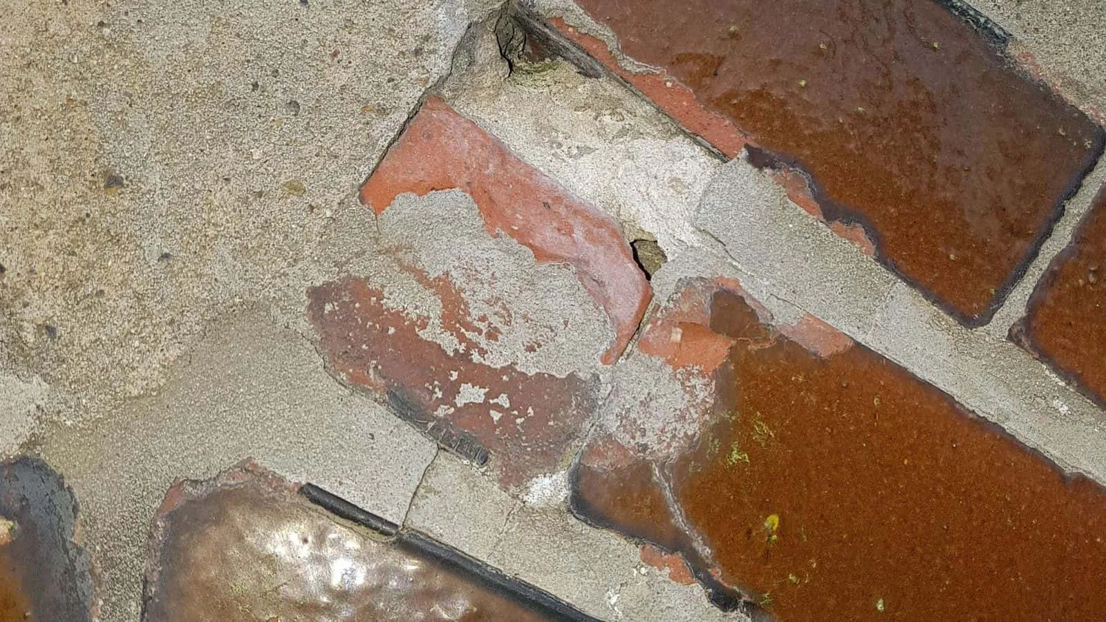 Ziegelwand mit abgeplatzter Oberfläche und hellen Putzresten