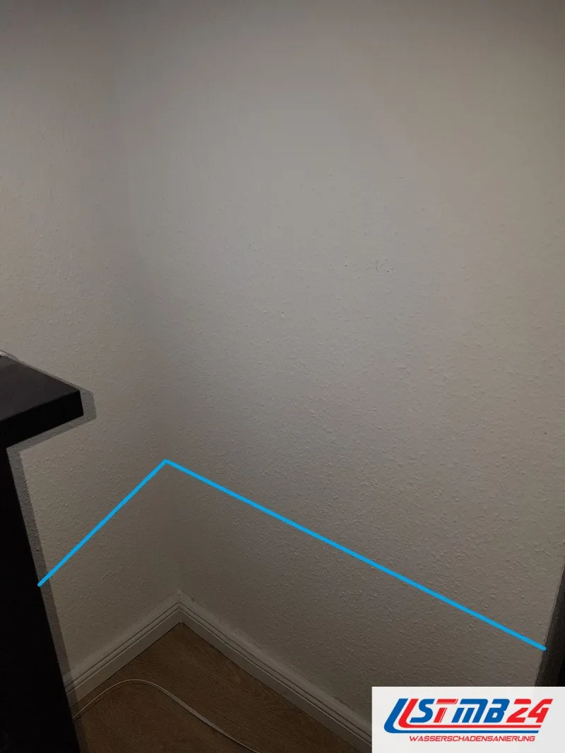 Helle Wandecke, eine blaue Linie zeichnet die Feuchtegrenze in der Wand nach