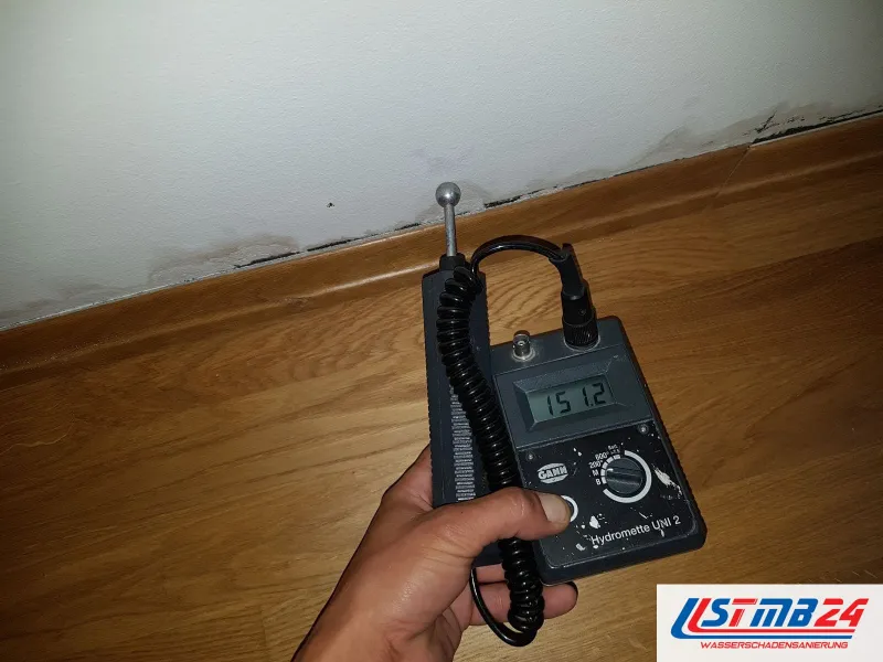 Messgerät mit Anzeige 151,2 am Wandfuß über Laminat, an der Wand dunkle Ränder
