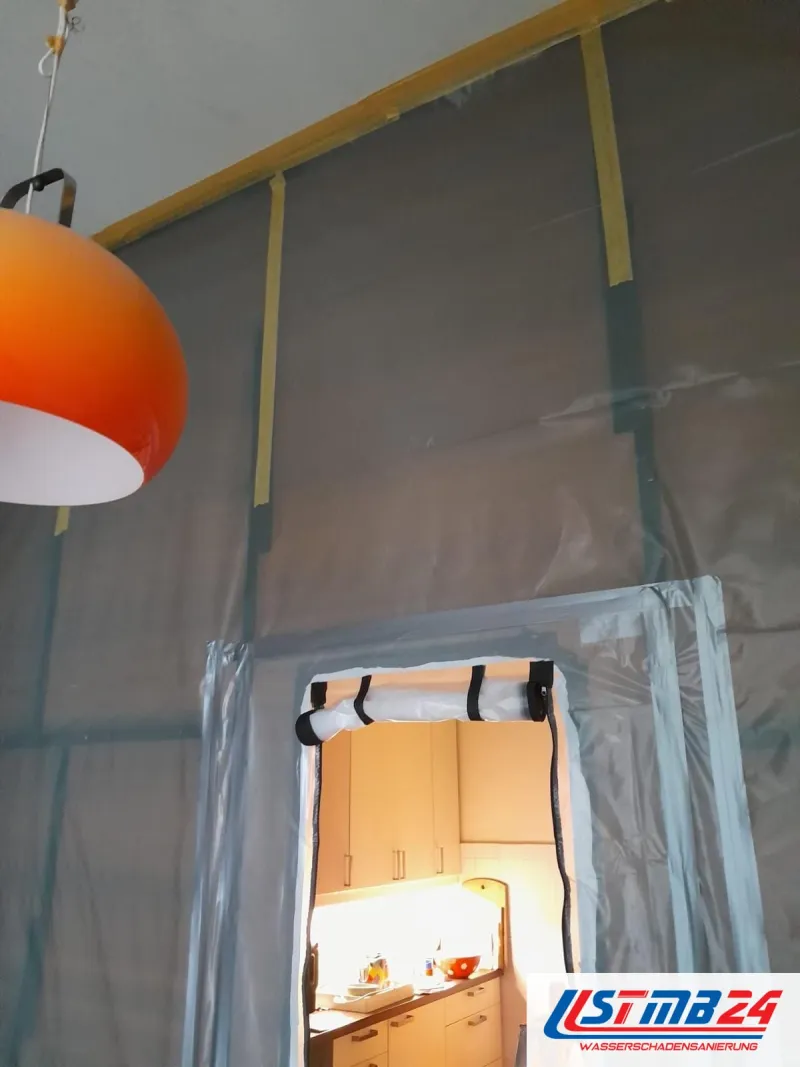 Wohnraum mit Folie an Wand und Decke abgeklebt, Reißverschlusstür zur Küche, Abluftschlauch über dem Durchgang, orangefarbene Lampe