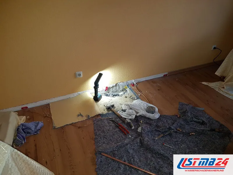 Zimmer mit Holzdielen, der Teppich an der Wand aufgenommen, darunter Filz, Werkzeug und eine Arbeitsleuchte am Wandsockel