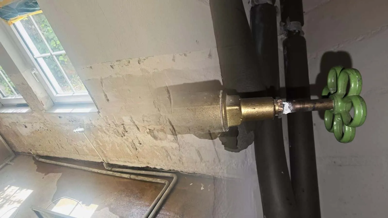 Absperrventil mit grünem Handrad an der Kellerwand