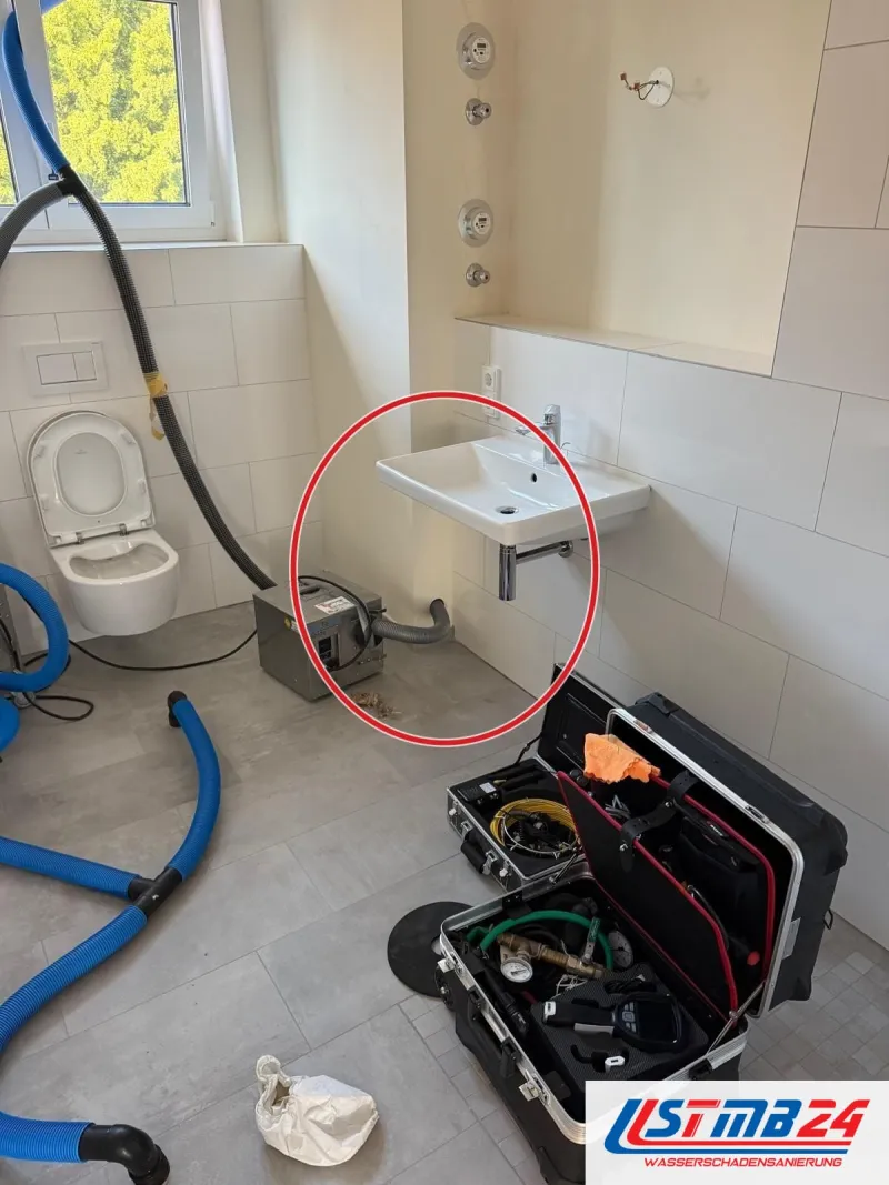 Bad mit blauen Trocknungsschläuchen und Verdichter neben dem WC, ein roter Kreis markiert die Stelle