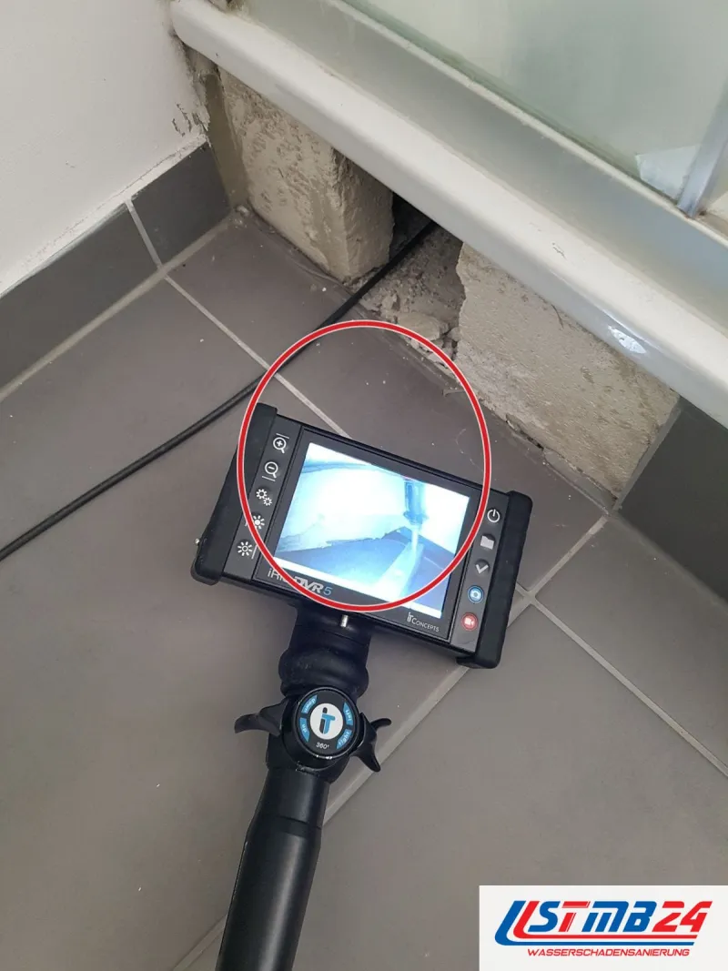 Endoskop mit Monitor auf grauen Bodenfliesen vor einer Wanne, ein roter Kreis markiert die Stelle