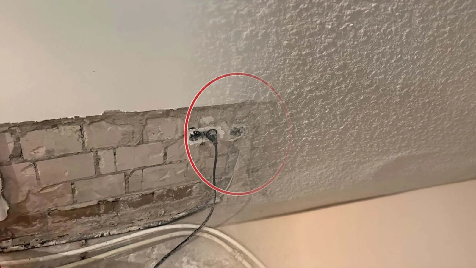 Raufaserdecke mit einer flachen Beule dicht an der Wand, das Papier hebt sich vom Untergrund ab