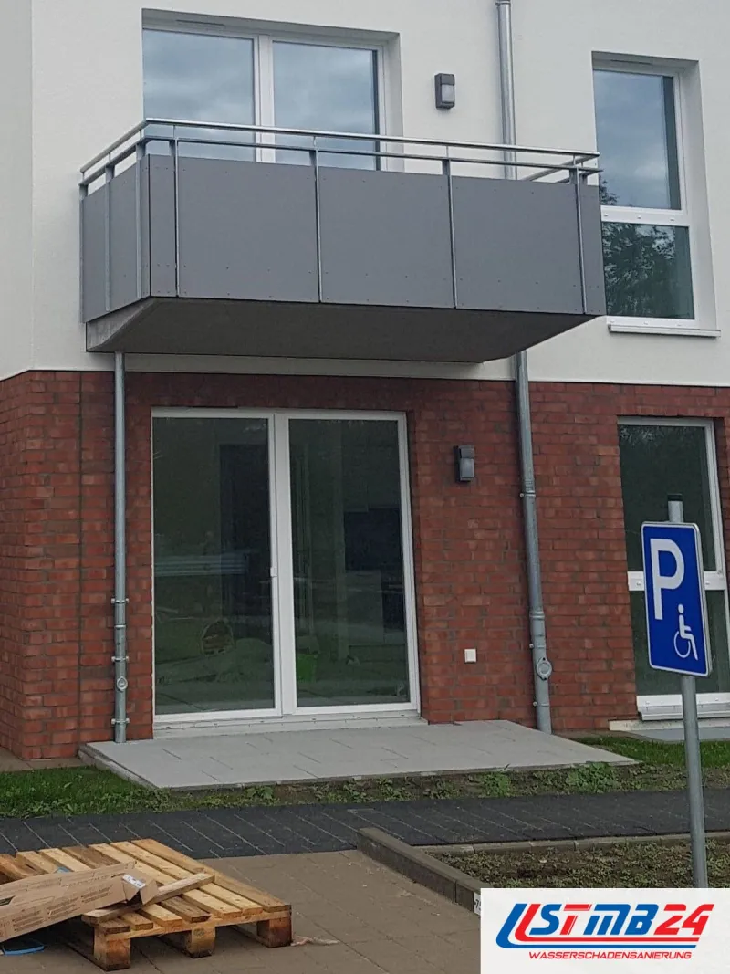 Mehrfamilienhaus im Neubau, unten Klinker, oben heller Putz, vor dem Eingang Paletten