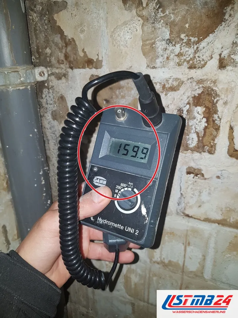 Hydromette an der Kellerwand mit Salzausblühungen neben einem grauen Fallrohr, Anzeige 159,9, ein roter Kreis markiert die Stelle