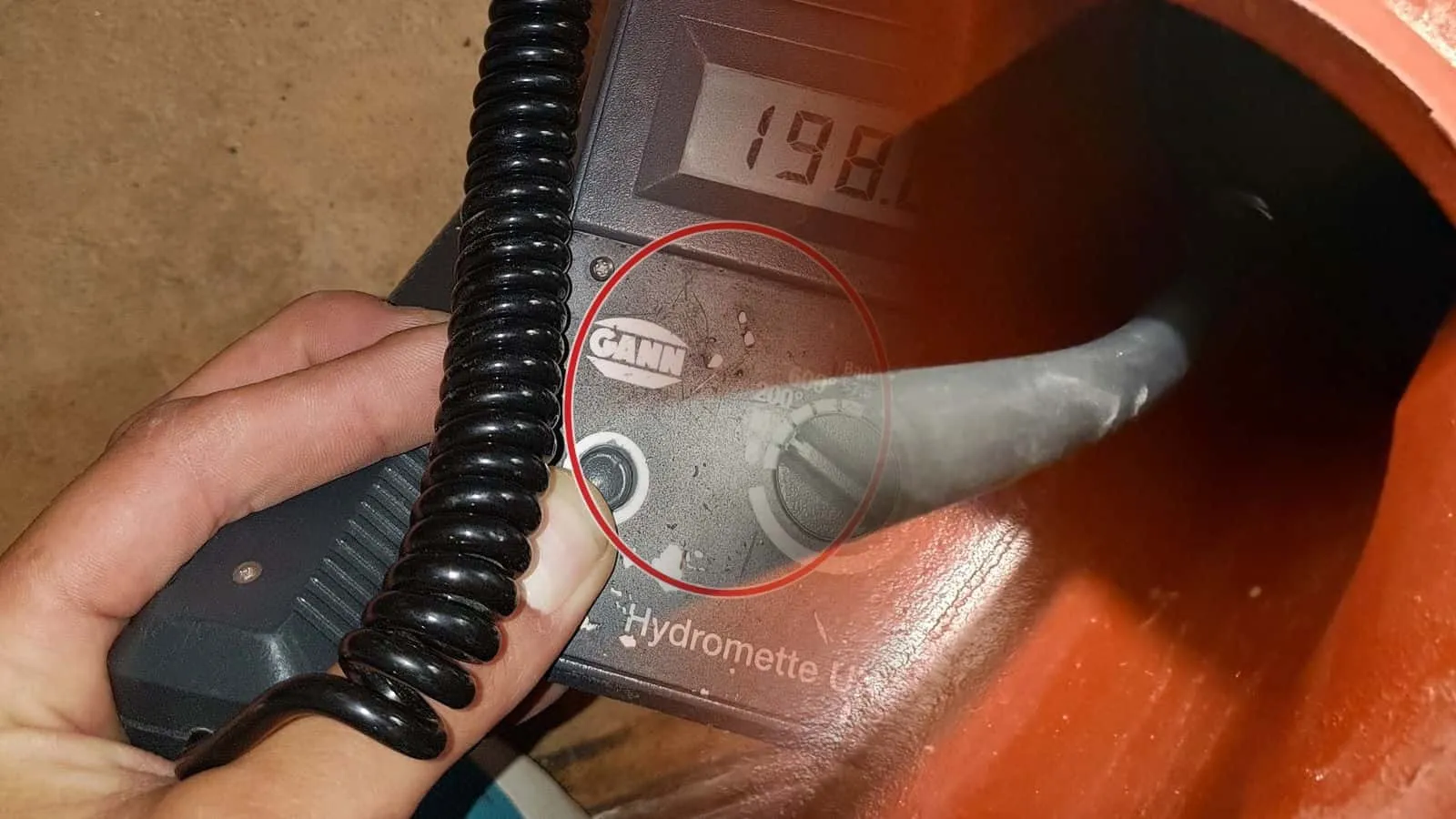 Blick in ein orangefarbenes Kanalrohr mit dem Kabel der Rohrkamera