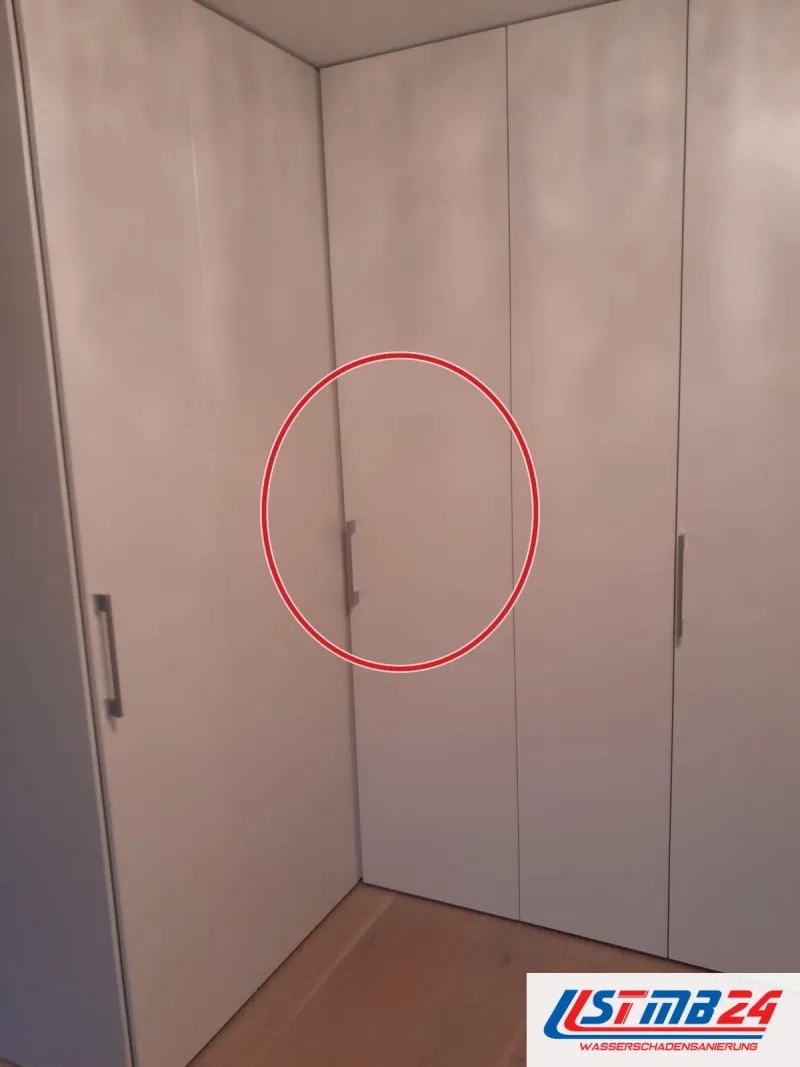 fertiger Einbauschrank über Eck mit weißen Türen und senkrechten Stangengriffen, ein roter Kreis markiert die Stelle