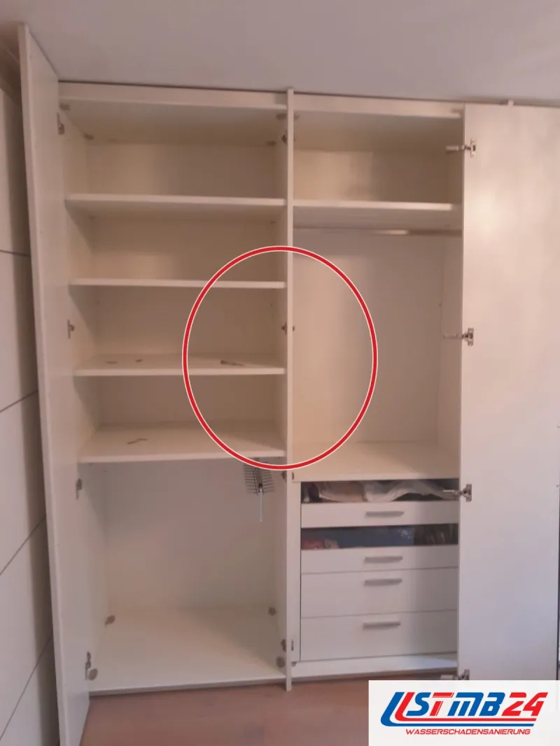 offener Einbauschrank mit Fachböden, Kleiderstange und Schubladen, die Türen stehen auf, ein roter Kreis markiert die Stelle
