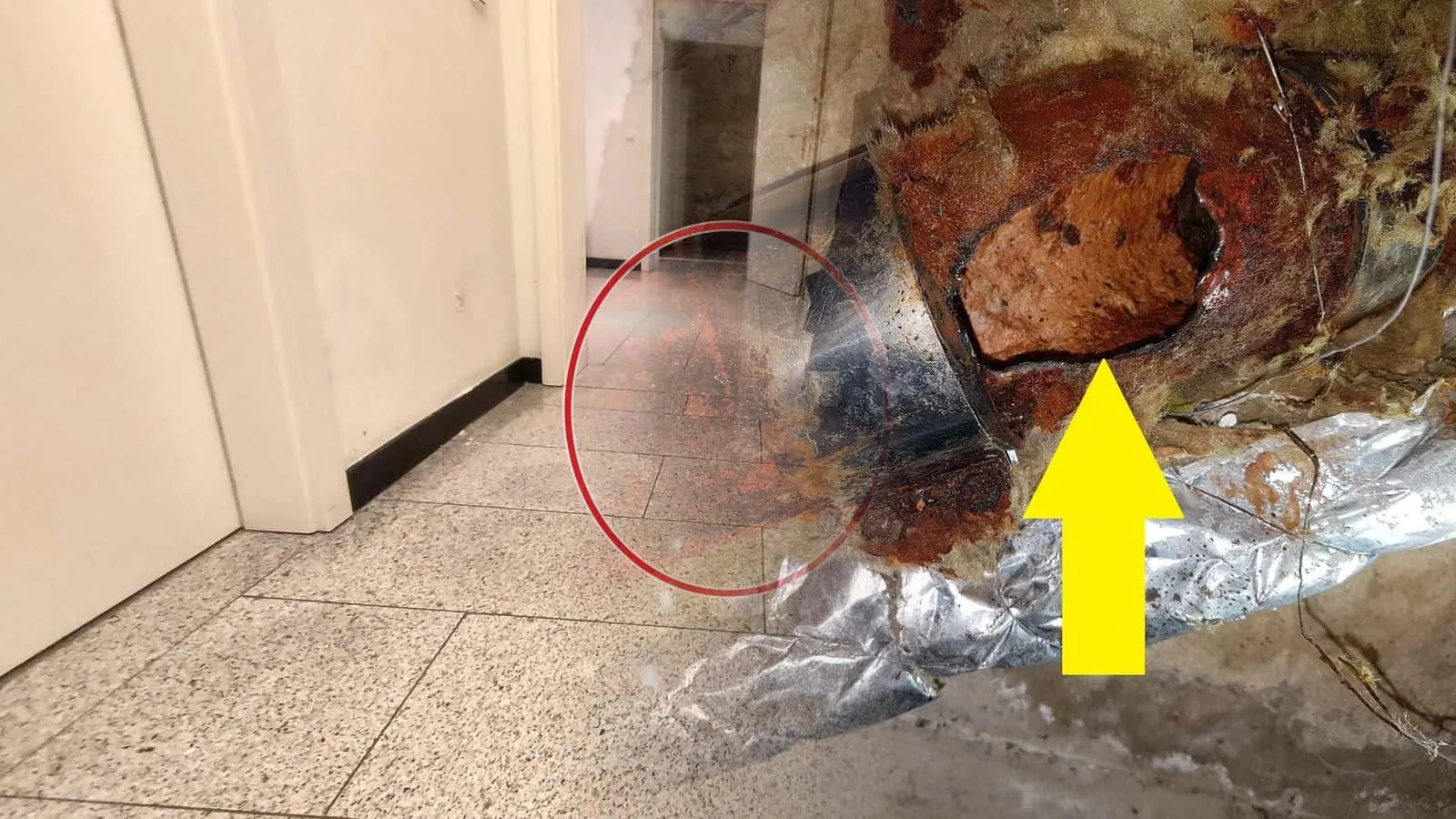Durchgerostetes Stahlrohr mit Loch an der Verbindung in Mineralwolle, gelber Pfeil auf die Bruchstelle, daneben alufolierte Leitungen