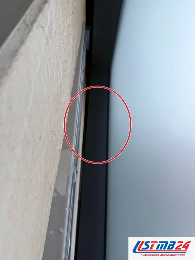Fensterlaibung mit abgeplatztem Putz am Rahmen, ein roter Kreis markiert die Stelle