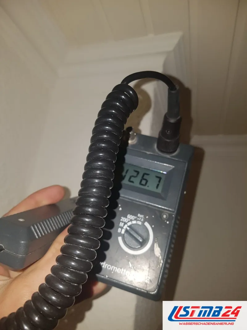 Messgerät mit Anzeige 126,7 an einer hellen Wandecke, die Kugelsonde liegt an der Wand