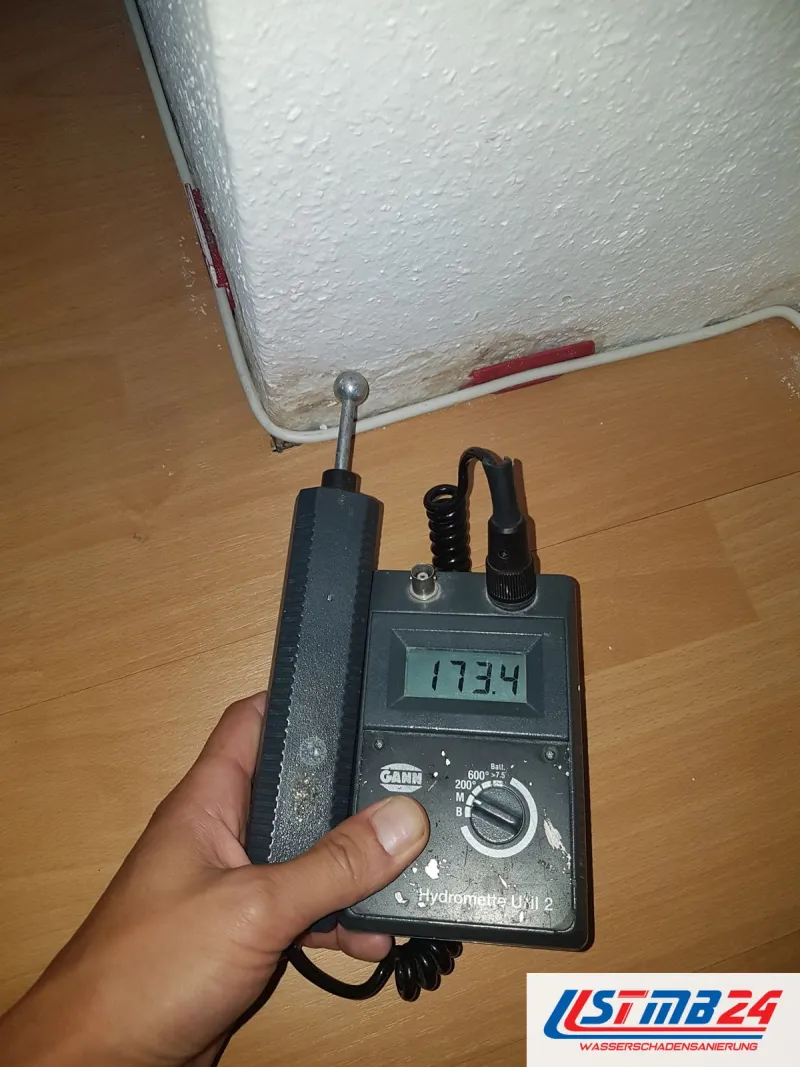 Feuchtemessgerät mit Anzeige 173,4 auf Laminat direkt an der Wand, am Sockel zeichnet sich ein heller Rand ab