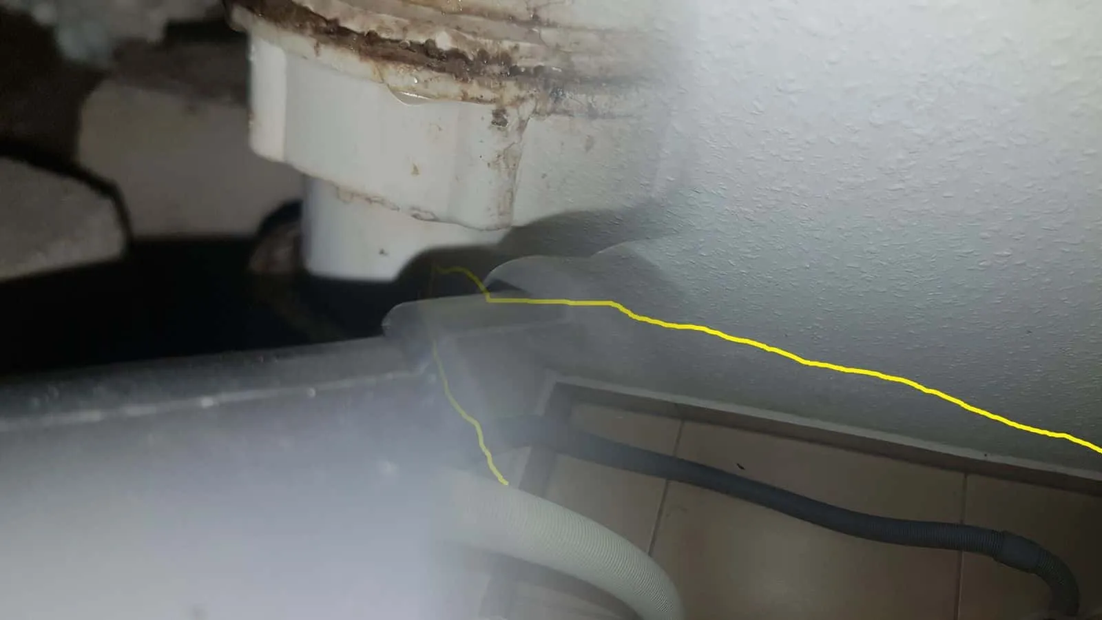Raufaser an Decke und Wand, die feuchte Fläche gelb umrandet, darunter zwei Trocknungsschläuche an der Fußleiste