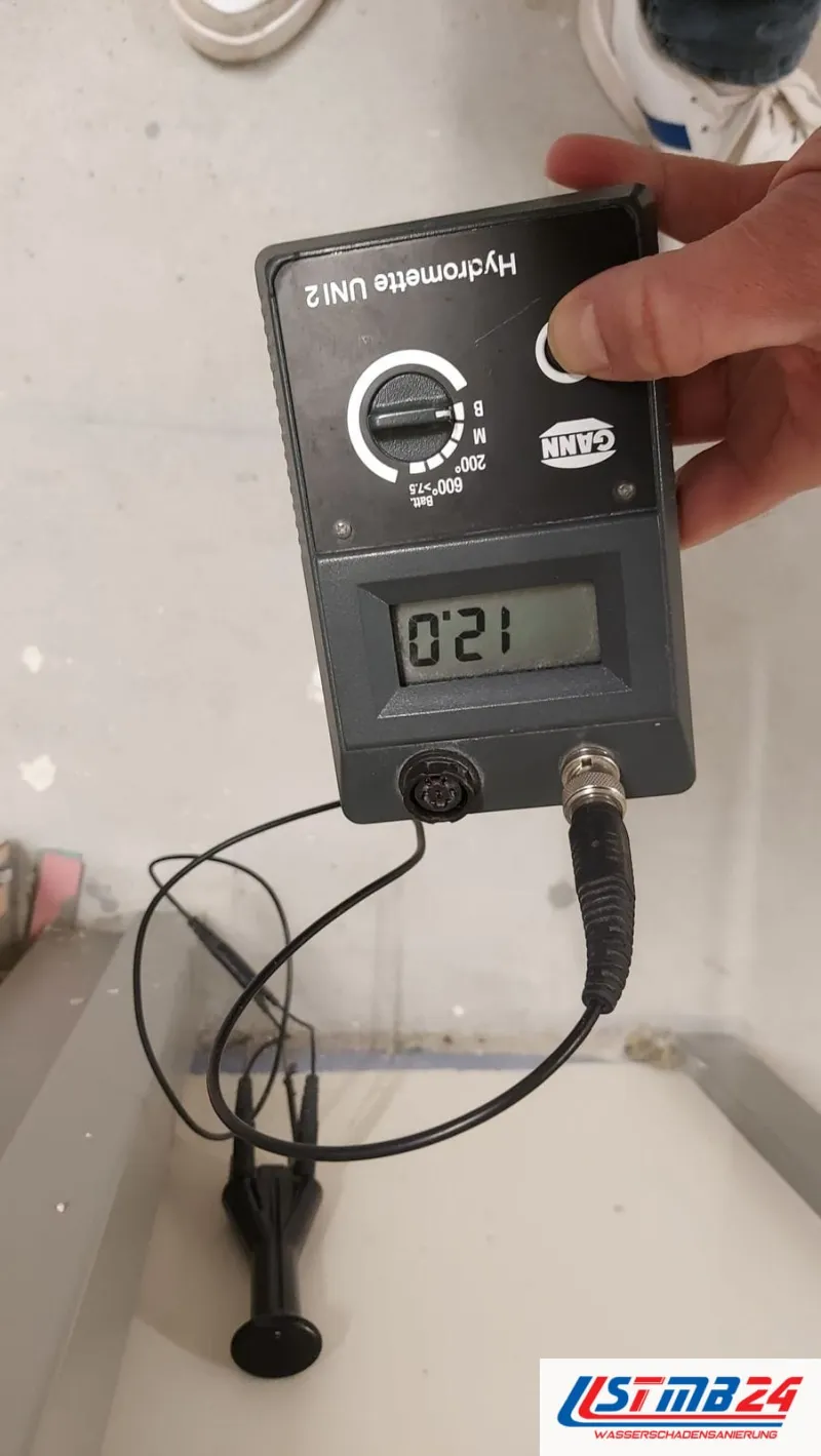 Feuchtemessgerät Hydromette mit Wert 12,0 auf einem Betonboden, Elektroden aufgesetzt, Kabel auf dem Boden