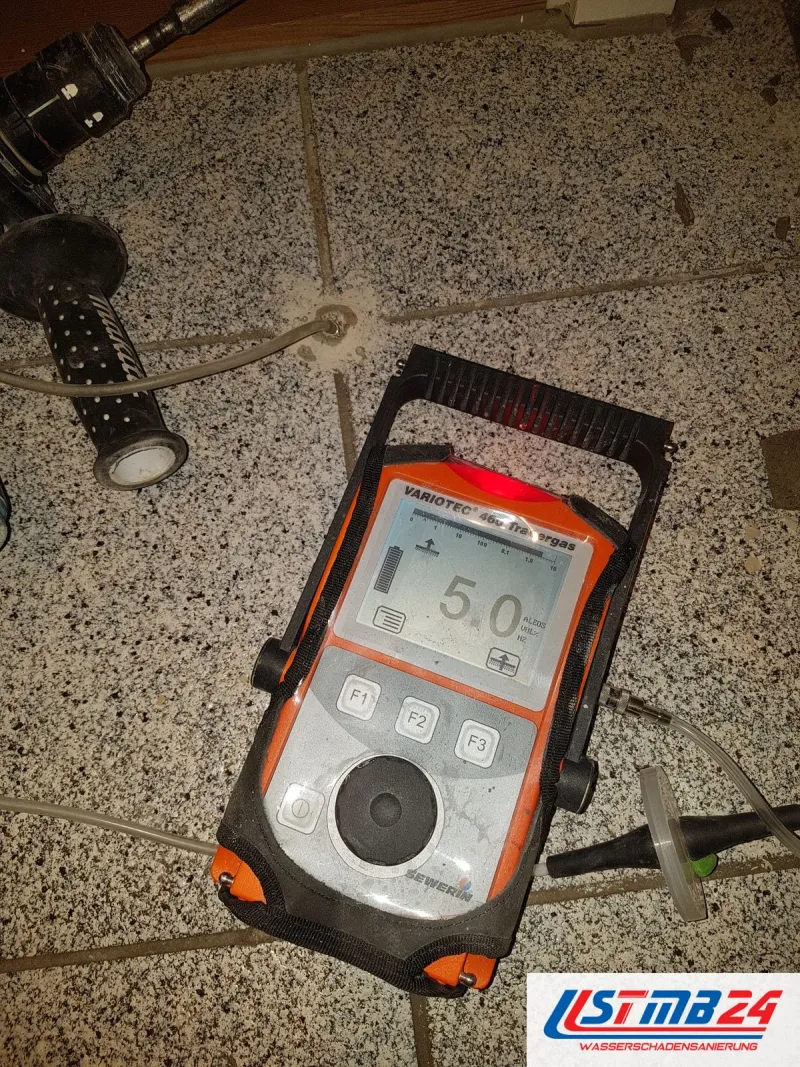 Gasspürgerät Variotec 460 zeigt 5,0 auf einem Terrazzoboden, daneben Bohrmaschine und Bohrloch für die Sonde
