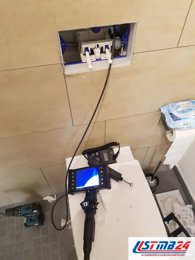 Endoskop mit Monitor in der Revisionsöffnung eines Unterputzspülkastens, Akkuschrauber auf dem WC-Deckel