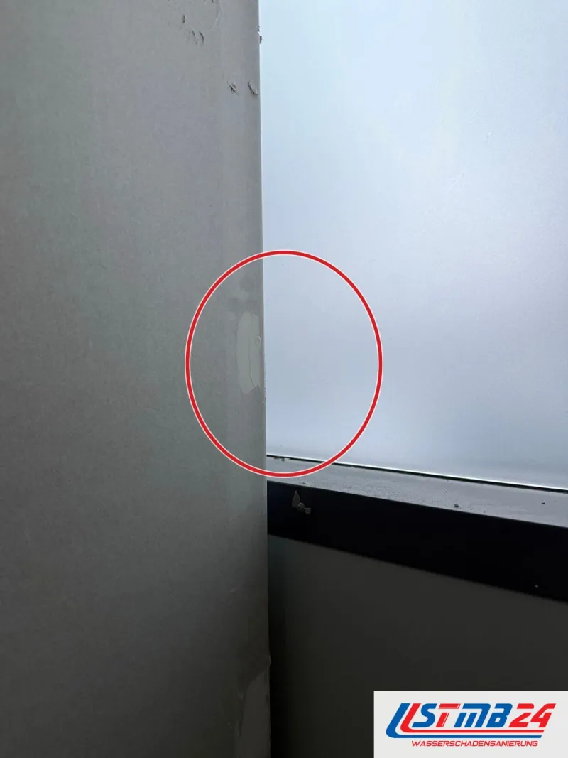 Fensterlaibung mit Spachtelstellen neben dunklem Rahmen und Milchglas, unten die schmale Fensterbank, ein roter Kreis markiert die Stelle