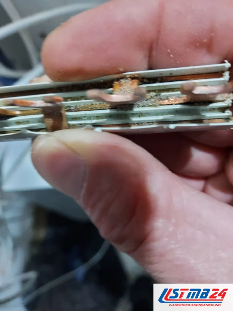 Elektroinstallation: ausgebaute Sammelschiene mit grüner Korrosion und Ablagerungen zwischen den Kupferstegen