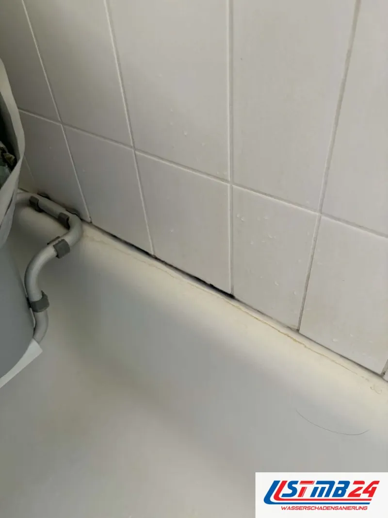 Fliesenarbeiten an der Badewanne: Silikonfuge zwischen Wanne und weißen Wandfliesen dunkel verfärbt und teils abgelöst