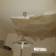 Decke mit großflächig abgelöster brauner Tapete über einer Hängelampe nach einem Wasserschaden aus der Wohnung darüber