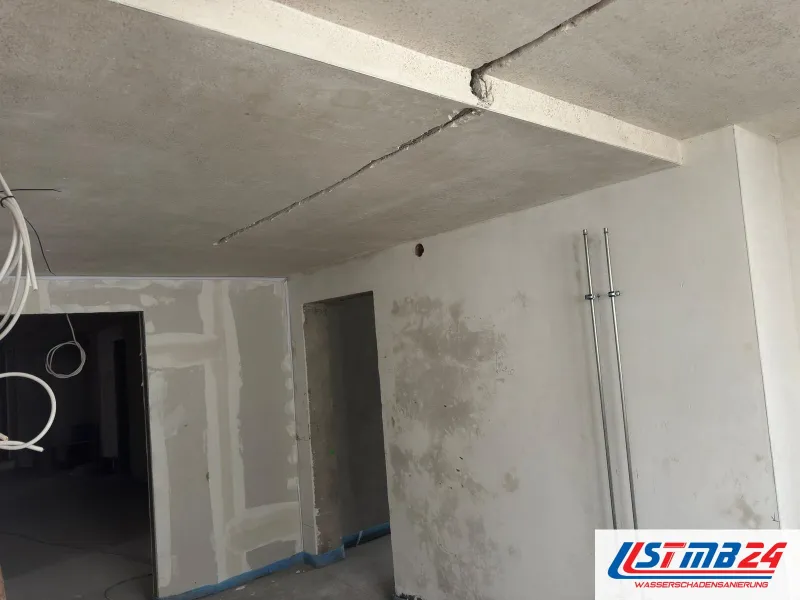 Neubautrocknung im Rohbau: Betondecke mit offenen Fugen, feuchte Flecken im frischen Putz neben zwei Steigrohren