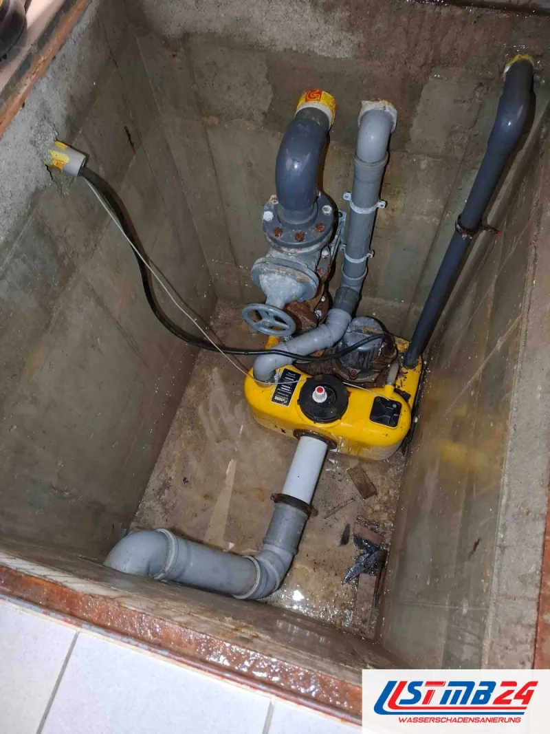 Sofortmaßnahmen bei Wasserschäden: gelbe Tauchpumpe im Pumpenschacht, Druckleitung mit Absperrschieber, unten steht Wasser