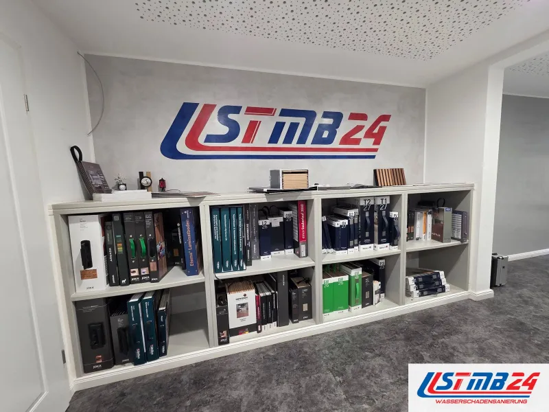Büro am Hauptsitz in Geesthacht: großes STMB24-Logo an der Wand, darunter ein Regal mit Musterkatalogen für Laminat, Vinyl und Fliesen