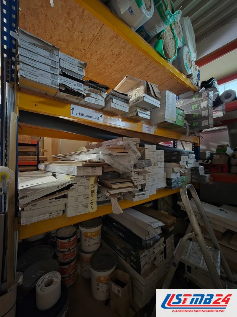 Regal im Lager in Geesthacht: Laminat- und Vinylpakete, darüber Rollen Trittschalldämmung, unten Eimer mit Spachtel und Farbe