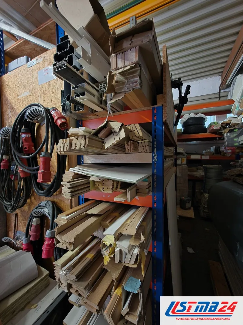 Lager in Geesthacht: Sockelleisten und Holzprofile im Regal, an der Wand Starkstromkabel mit roten CEE-Steckern