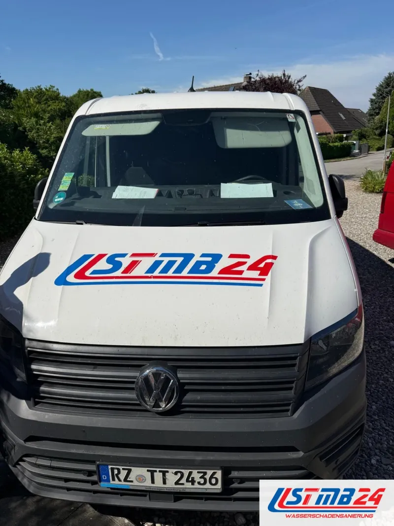 STMB24 in Geesthacht: weißer VW-Transporter mit großem Logo auf der Motorhaube in einer Wohnstraße