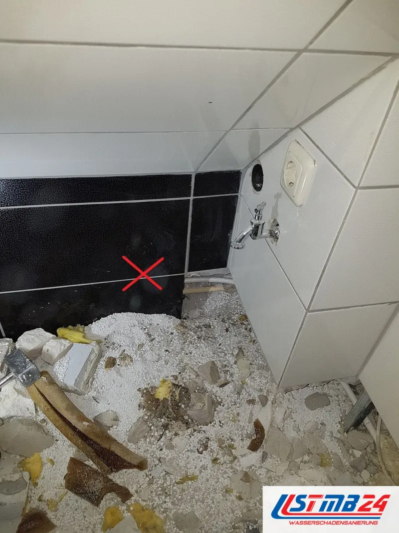 Badsanierung in Geesthacht: Rückbau unter der Dachschräge, Schutt mit Styroporkügelchen, ein rotes Kreuz markiert die schwarze Fliesenwand