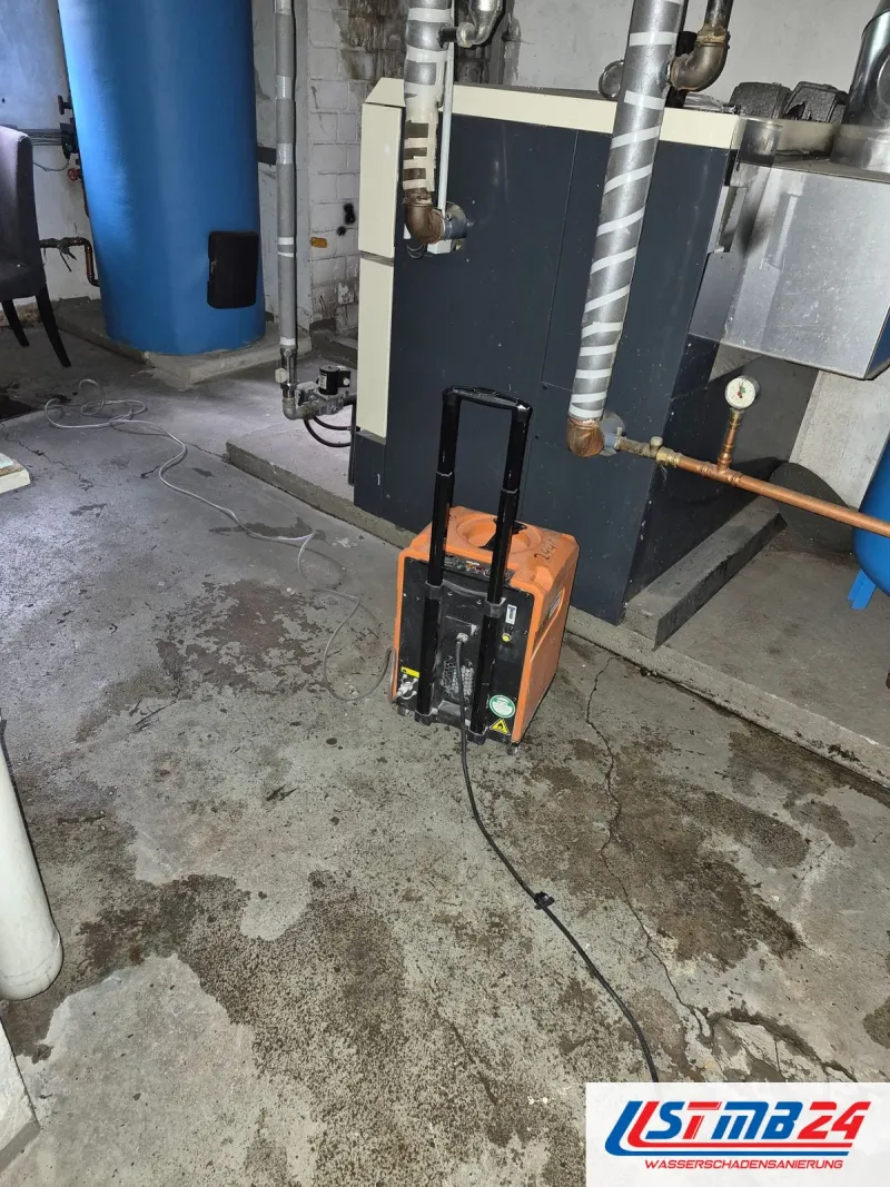 Bautrocknung in Geesthacht: orangefarbener Heylo-Trockner auf nassem Boden im Technikraum zwischen Kessel und Speicher