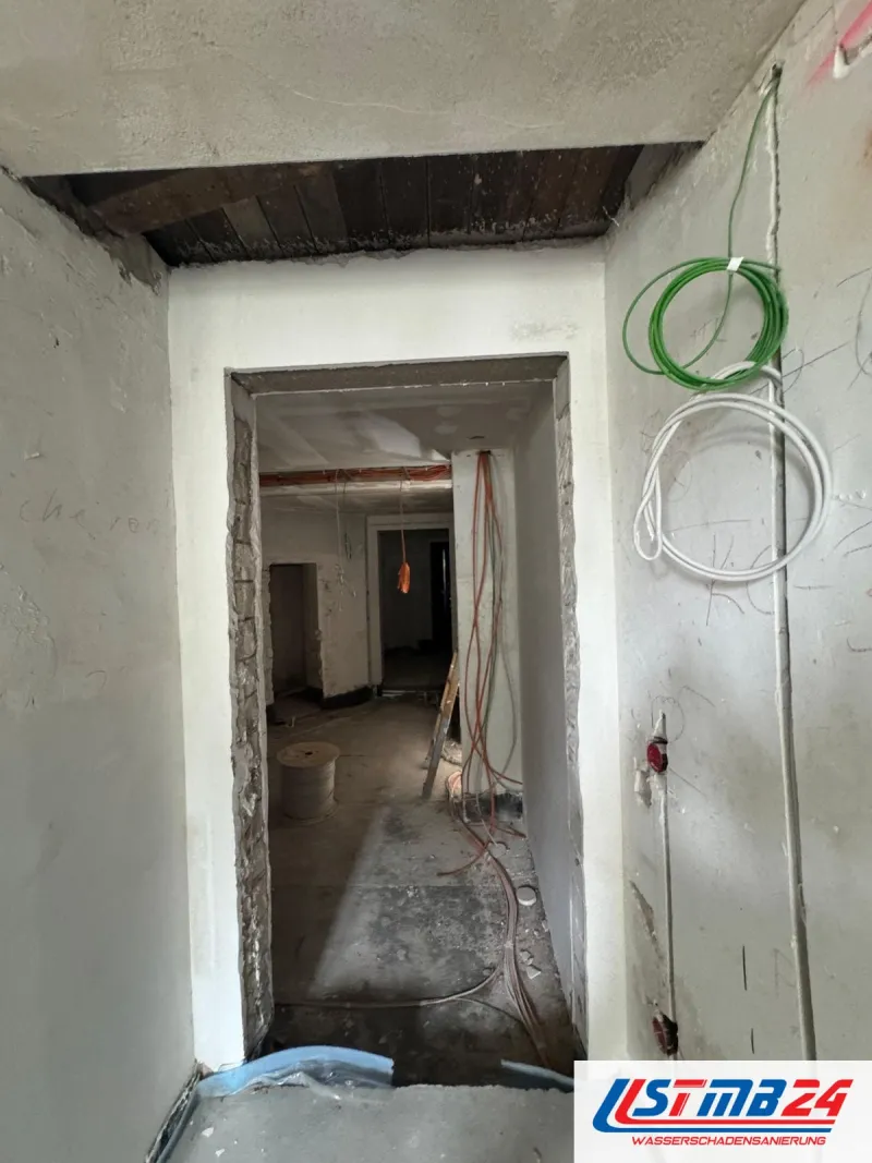 Elektriker in Geesthacht: entkernter Altbauflur, an der Wand hängen grüne und weiße Leitungen, hinten Kabel aus der Decke