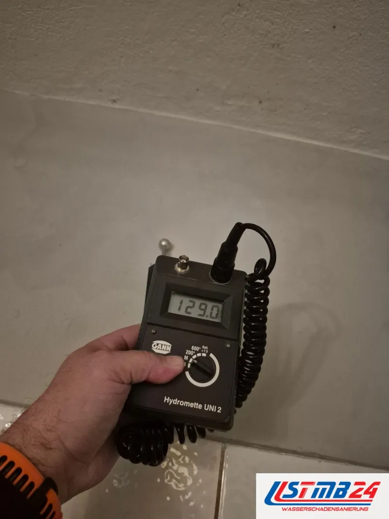 Feuchtigkeitsmessung in Geesthacht: Kugelsonde an der hellen Wand über weißen Bodenfliesen, die Hydromette zeigt 129,0