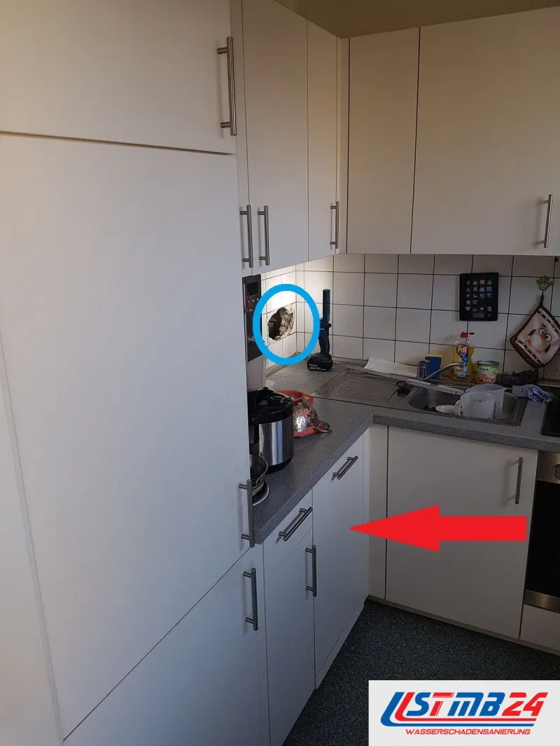 Küchenmontage in Geesthacht: Küche mit Hochschrank, ein blauer Kreis um eine Öffnung in der Fliesenwand, ein roter Pfeil auf den Unterschrank