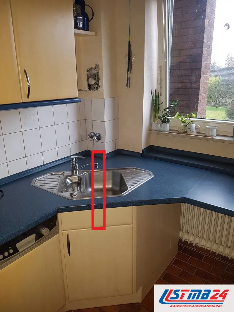 Küchenmontage in Geesthacht: Eckspüle mit blauer Arbeitsplatte, ein roter Rahmen markiert den Unterschrank, oben ein Loch in der Wand
