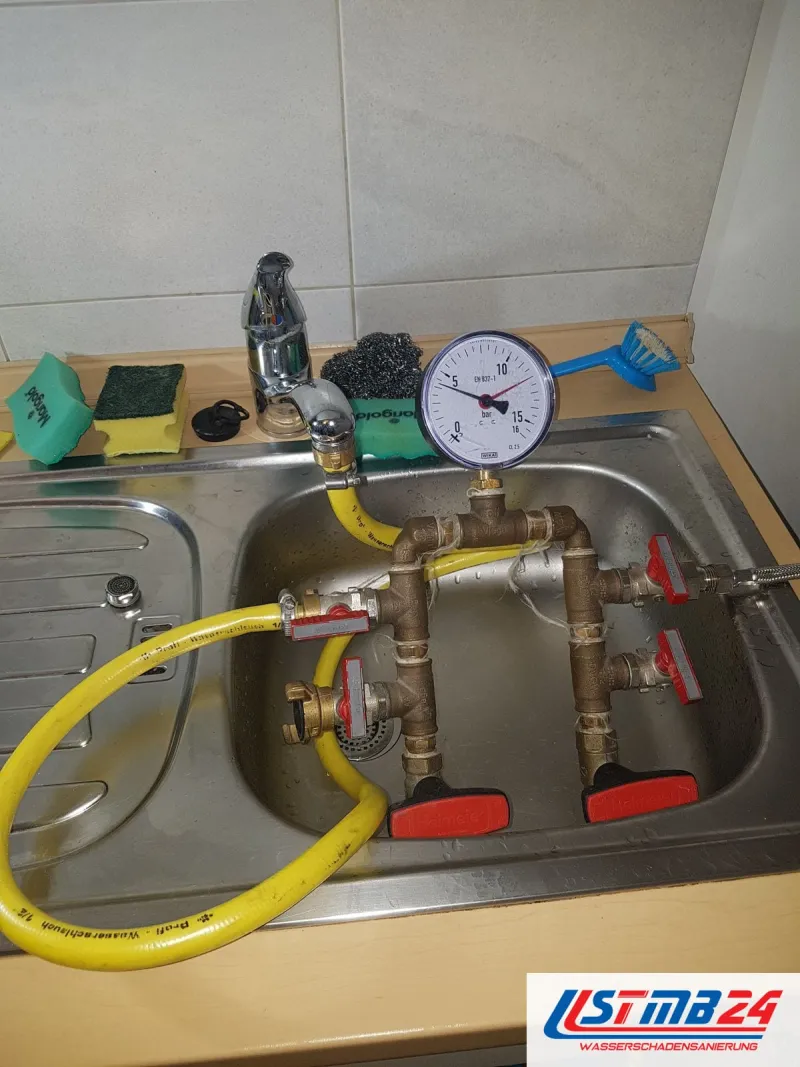 Leckortung in Geesthacht: Prüfarmatur aus Messing mit Manometer und roten Kugelhähnen im Spülbecken, Zulauf vom Wasserhahn