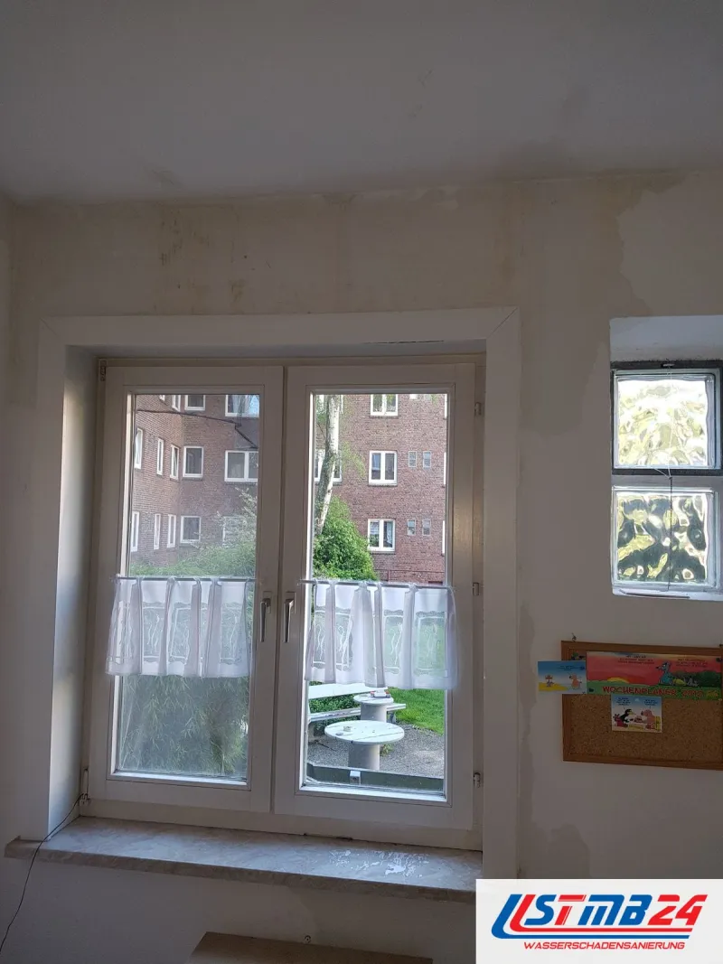 Maler in Geesthacht: Raum vor der Renovierung, Wand rund um das Fenster mit Flecken, rechts ein Glasbausteinfenster