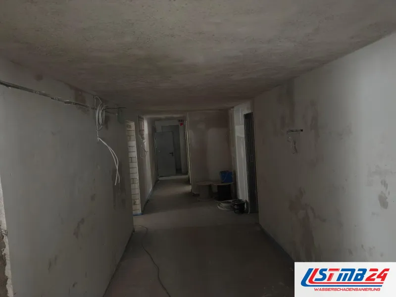 Maler in Geesthacht: langer Flur im Altbau mit gespachtelten Wänden, offene Leitungen und eine Kabelrolle am Boden