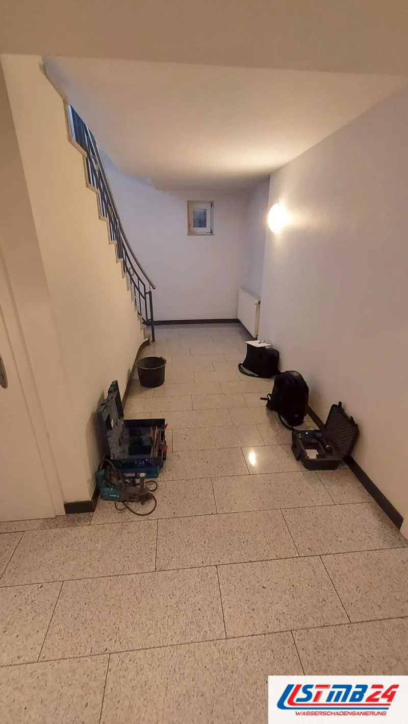 Wasserschaden Notdienst in Geesthacht: Werkzeugkoffer, Messkoffer, Rucksack und Eimer stehen im Hausflur unter der Treppe