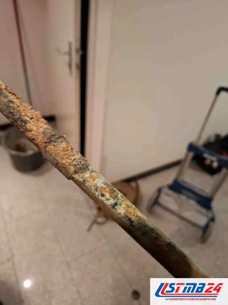 Rohrbruch in Geesthacht: ausgebautes Rohr mit Rost und grüner Korrosion auf ganzer Länge, im Hintergrund eine Sackkarre