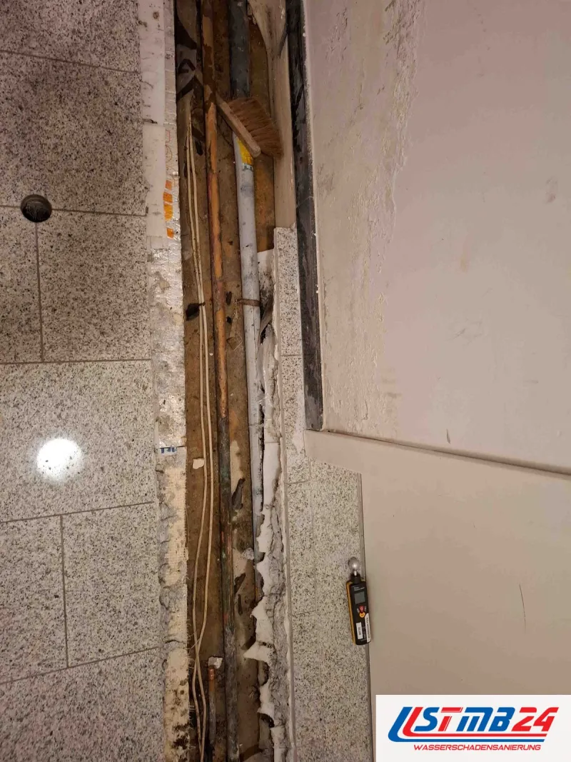 Sanitär und Heizung in Geesthacht: geöffneter Leitungskanal im Granitboden des Flurs, daneben ein Messgerät an der Wand