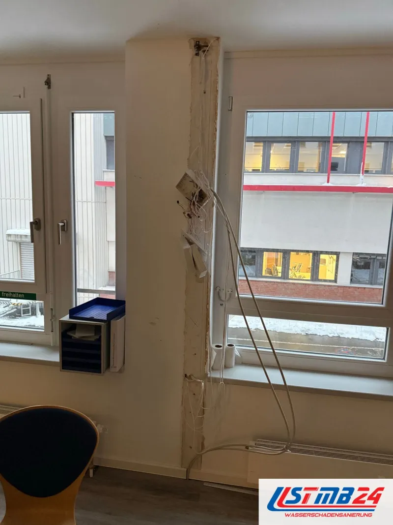 Tischler in Geesthacht: Bürofenster mit geöffneter Pfostenverkleidung, Kabel hängen heraus, draußen ein Bürogebäude