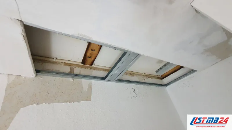 Trockenbau in Geesthacht: Deckenöffnung in der Gipskartondecke, darüber Metallprofile, Holzbalken und eine Leitung