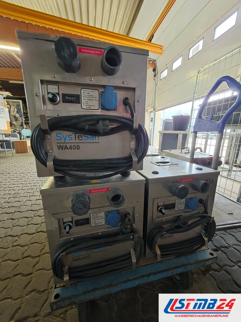Trocknungsgerät mieten in Geesthacht: drei SysTeSan WA400 mit aufgewickelten Kabeln auf einem Transportwagen in der Halle
