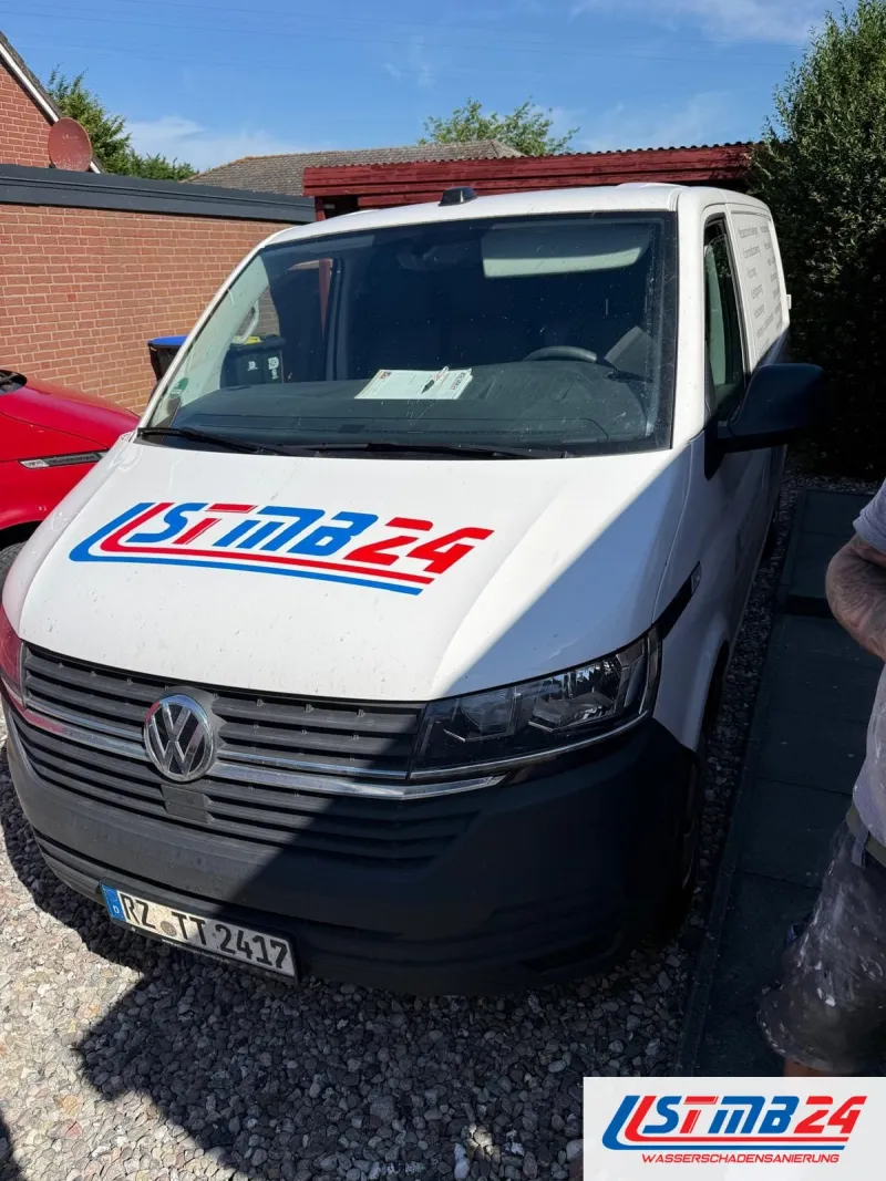 STMB24 in Grömitz: weißer VW-Bus mit Firmenlogo auf der Haube in einer Einfahrt mit Carport